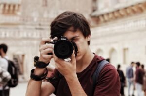 Young man holding a Nikon camera to his face in an urban space