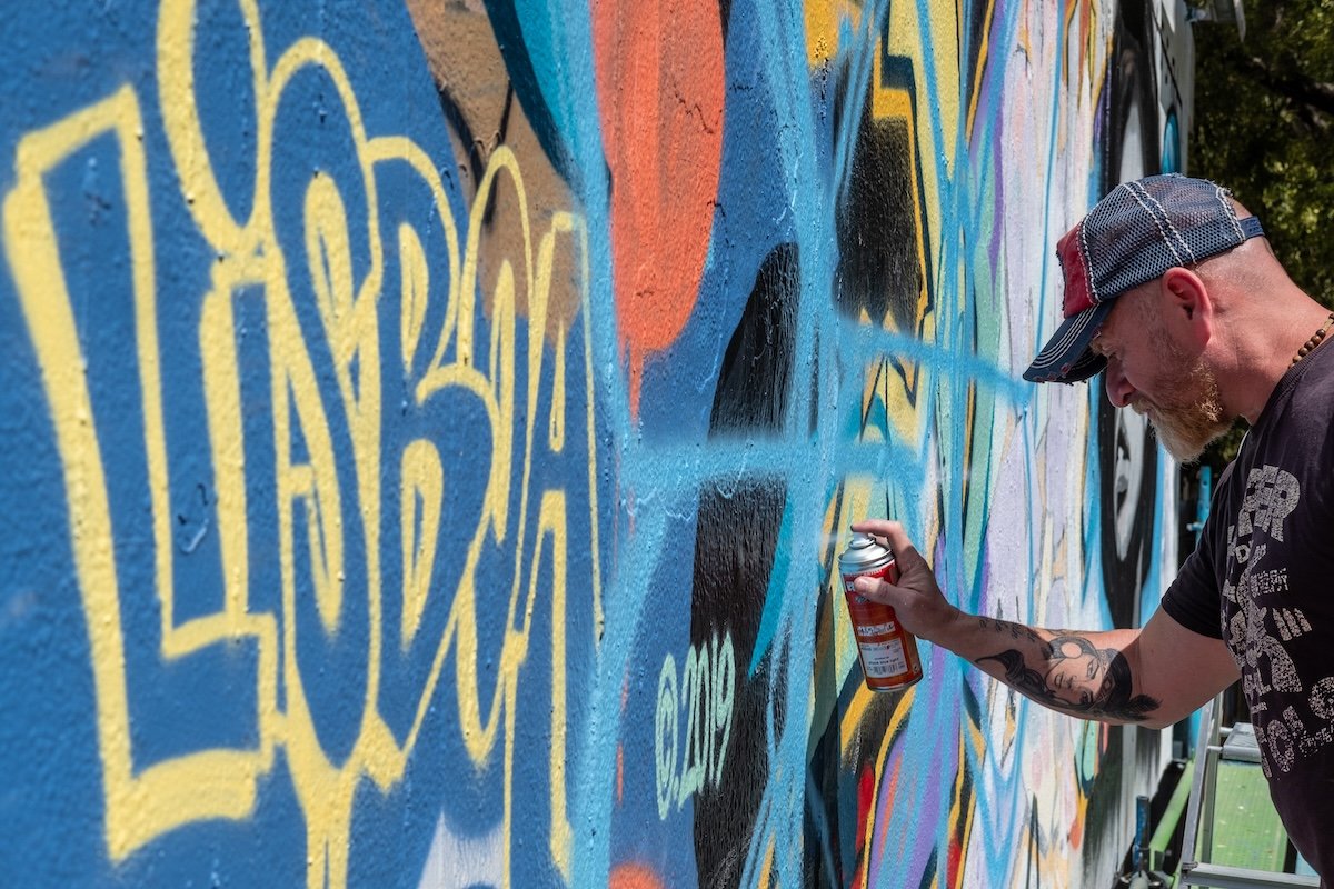 Photo of a graffiti artist spraying painting a wall shot with a street photography camera