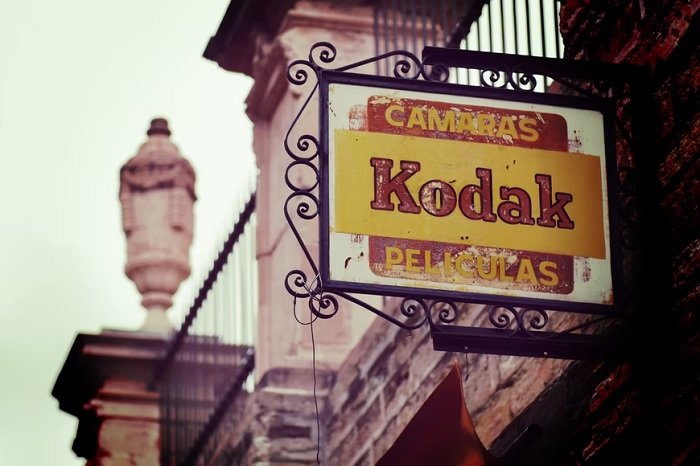 Old shop sign that says Kodak cameras and peliculas