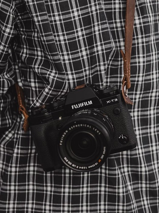 Fujifilm camera strapped around someone's shoulder