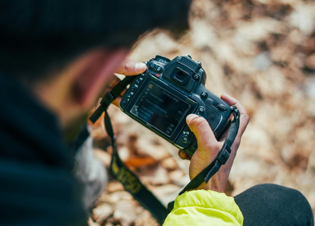 photograph of man looking through camera settings