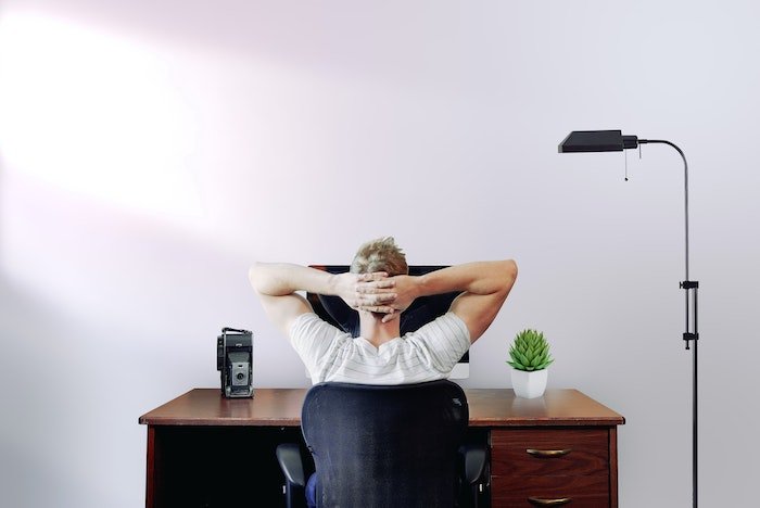 Man relaxing in front of his computer with a vintage camera on desk