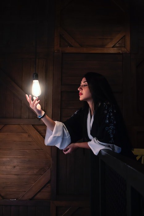 low light photography idea: a single light bulb illuminates a portrait of a woman 