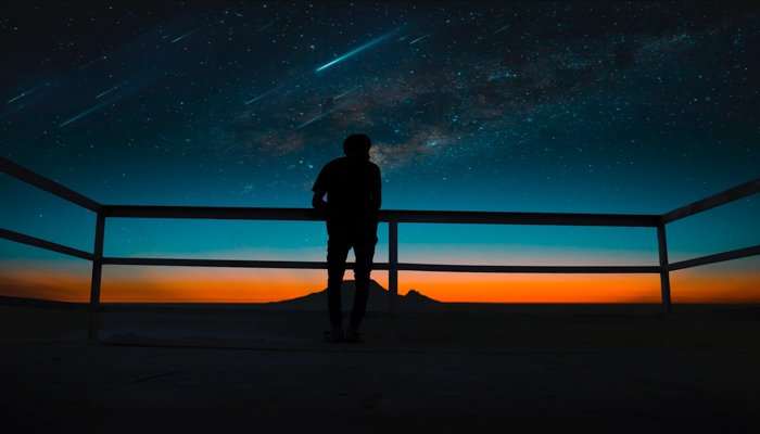 The silhouette of a man watching a meteor shower