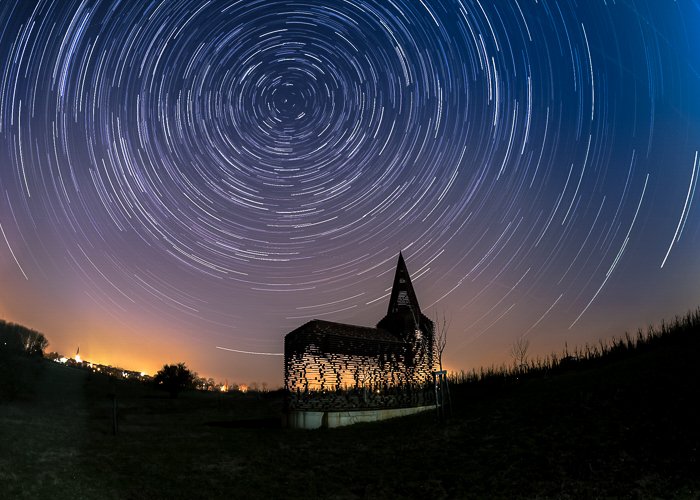Stunning photo of star trails over a church at night