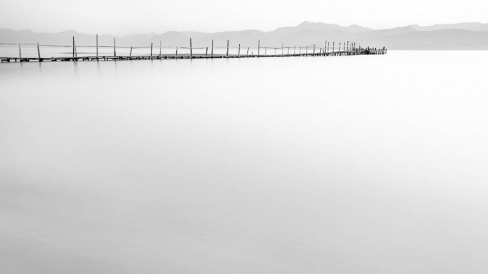 Minimal photo of a dock in Kalamaki beach at dawn. (Kerkyra, Greece), demonstrating smooth motion blur