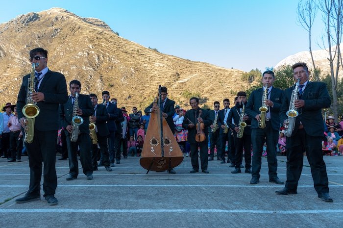 A group of people playing instruments outside with a sunny mountain behind them
