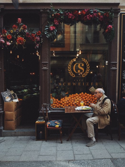 an old man sitting alone and eating outside a restaurant 