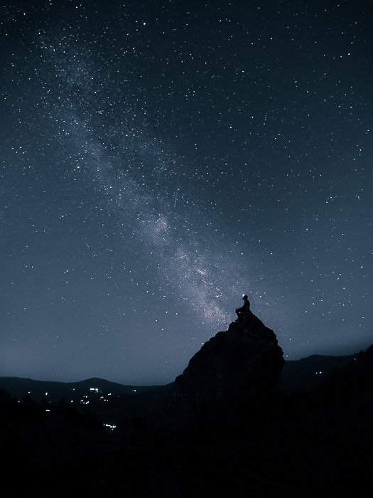 A person sitting on a rock in silhouette against the sky (nearby Bobbio, Italy)