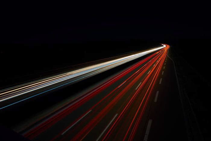 Streaming red and white light trails on a dark background shot at f/13 with a shutter speed of 25 seconds at ISO 100