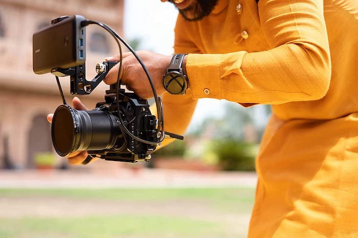 A person holding a Nikon Z8 mirrorless camera with an external screen attached