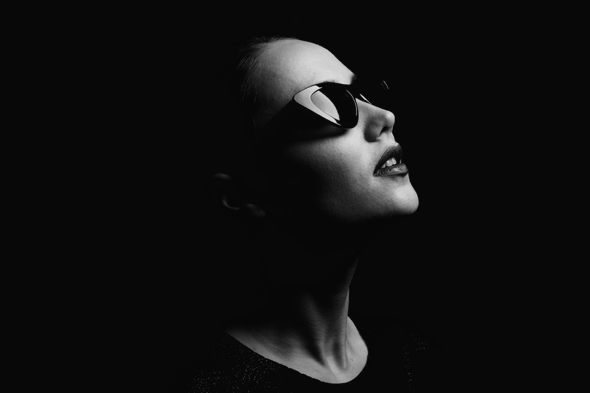Black-and-white low-key portrait of a woman wearing sunglasses