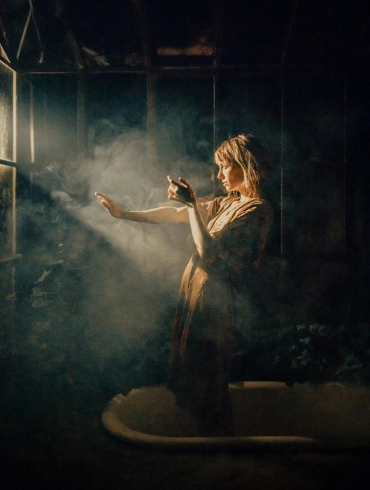Woman standing in the smoky light of a window