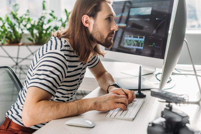 Man with long hair editing photos on a computer
