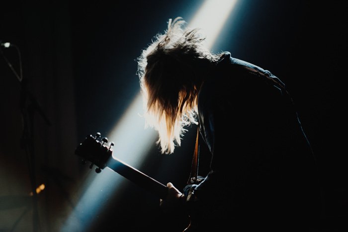 A concert photography image of a guitarist onstage