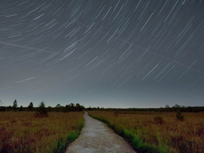 star trails photography over the high fens plateau in Belgium, with a road in the foreground