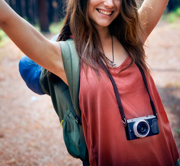 A young travel photographer posing with her camera