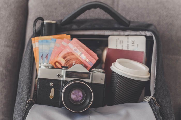 Opened backpack with things needed for travel photography like camera, money, passport and tickets