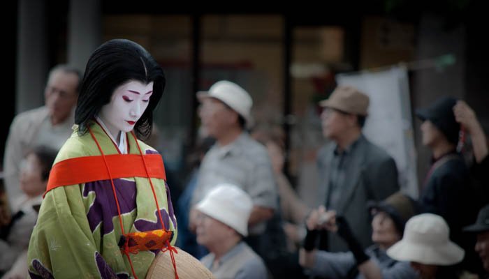 A street photo of a Japanese women wearing geisha attire