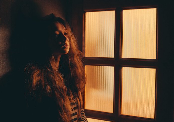 Portrait photo of a girl next to a window in tungsten light